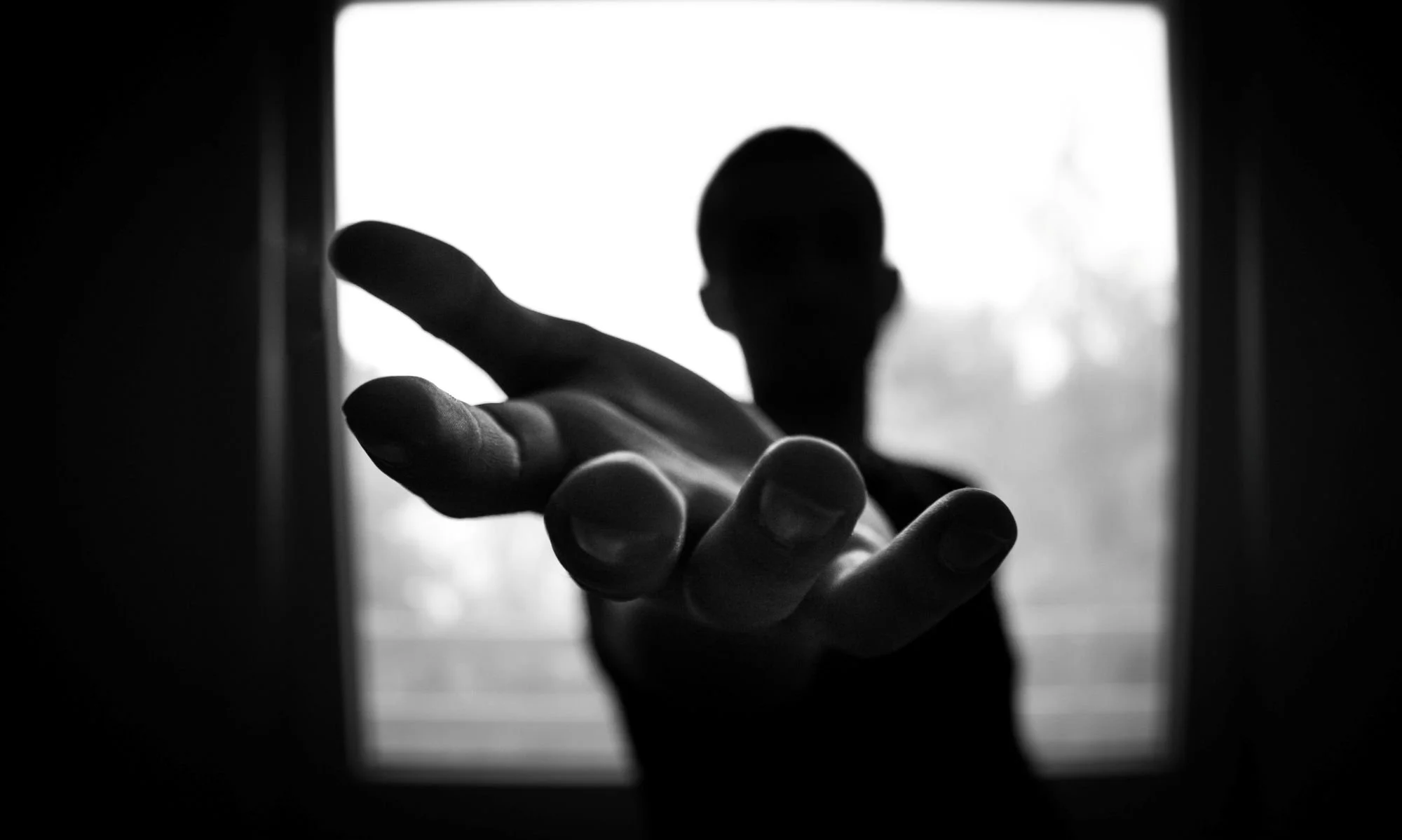 a person standing with their hand outstretched with a window in the background