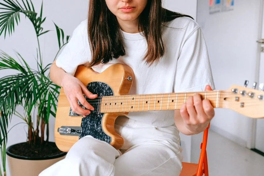 Woman sitting with guitar on lap about to play it