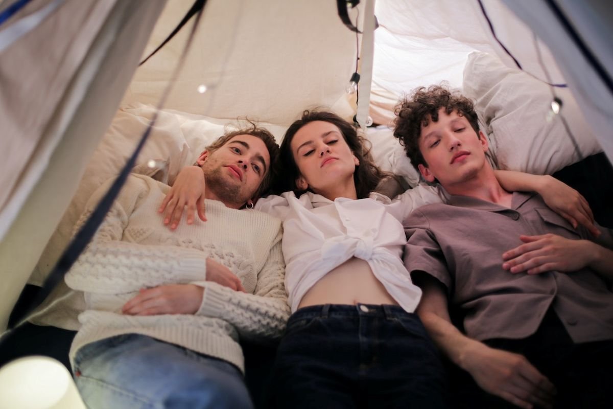 woman and 2 men lying in tent