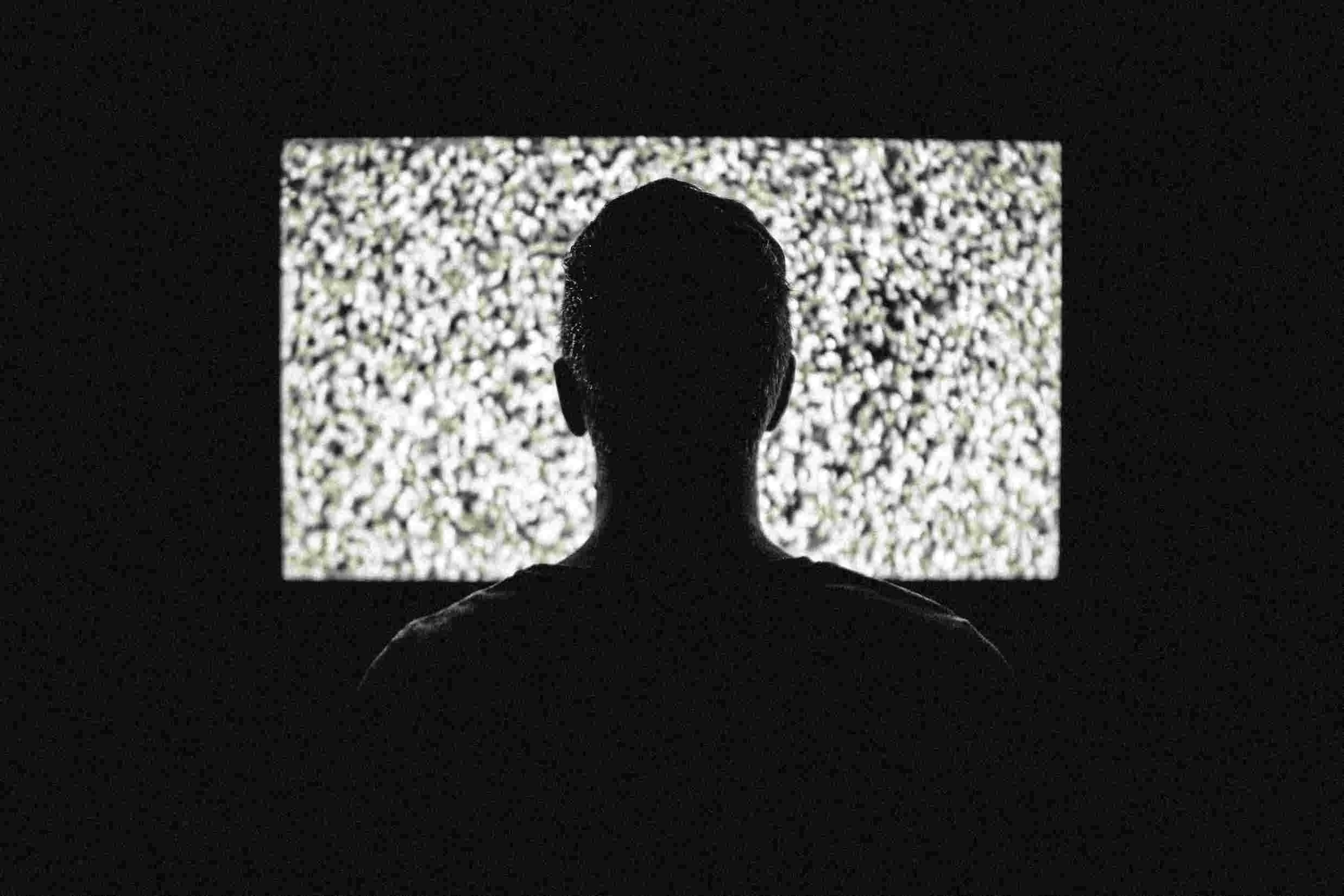 Person staring at a blank screen in the dark