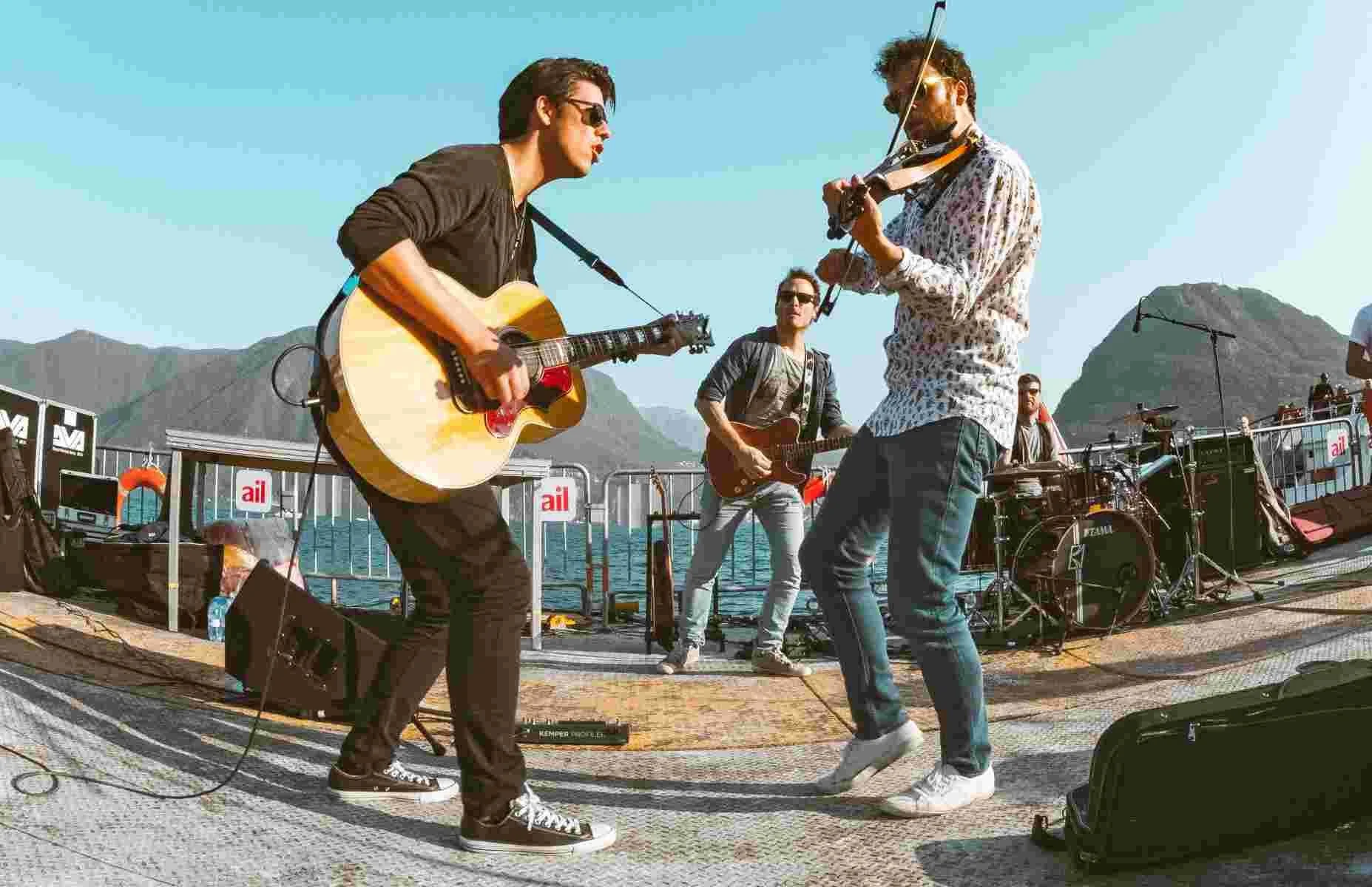 A band playing onstage in front of a body of water