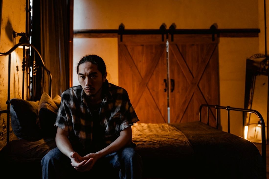 Image of man sitting on bed by himself