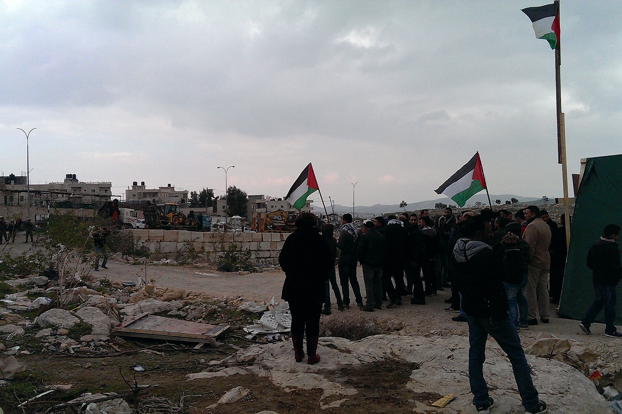 Palestinians chant in front of soldiers at the entrance of the campsite