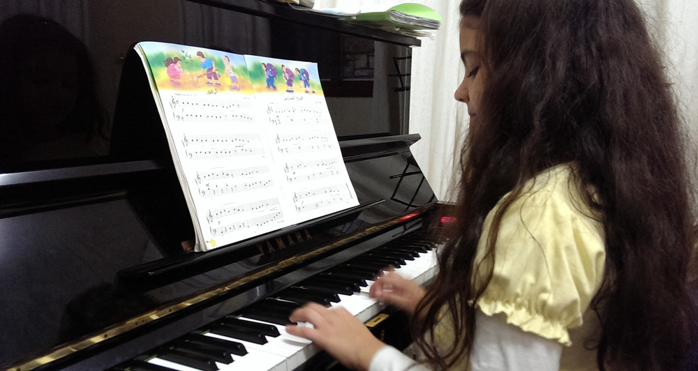 9-year old Joanna plays piano at Edward Said Music Academy in Gaza, Nov. 10, 2013 ©Lena Odgaard