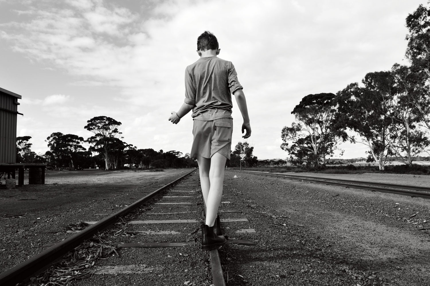 Boy walking along railway line. bella magazine