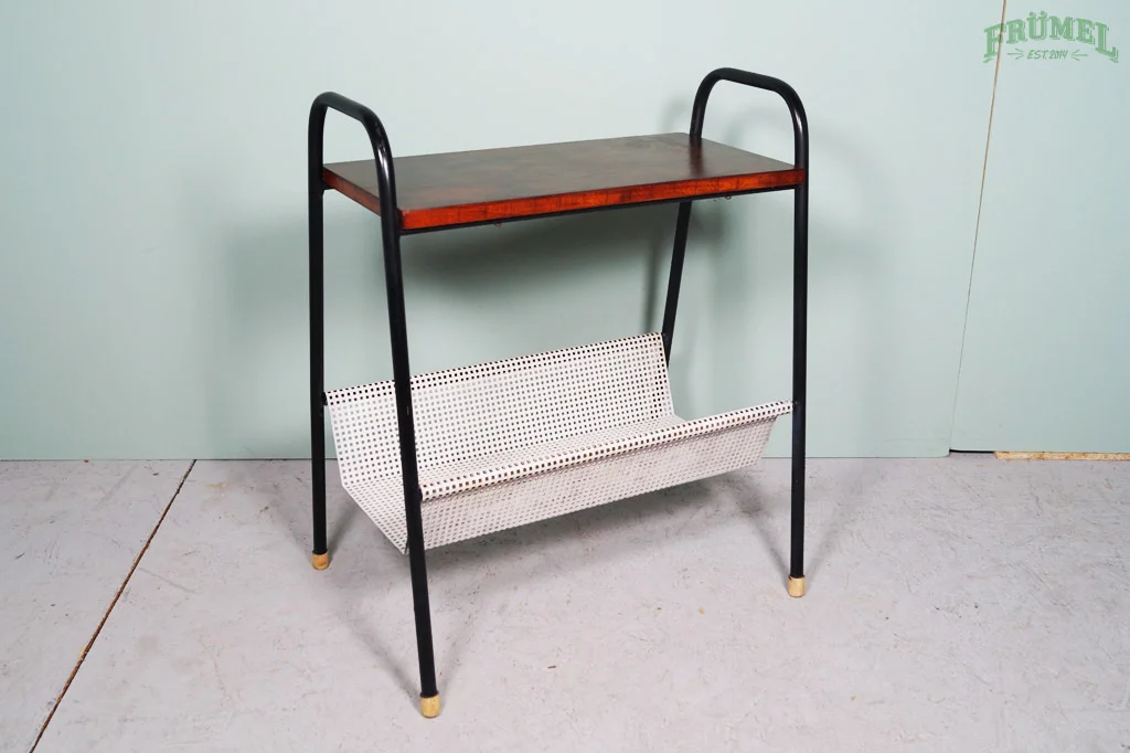 Een metalen en houten tafel met een witte mand onder de tafel, tegen een lichte groene muur.