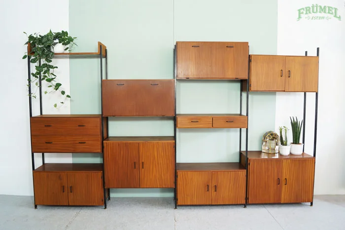 Teakhouten Simplalux wandsysteem op een zwart metalen frame met planten en decoratieve items.