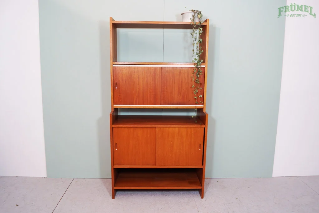Een houten kast met open en gesloten compartimenten, naast een plant op de bovenste plank.