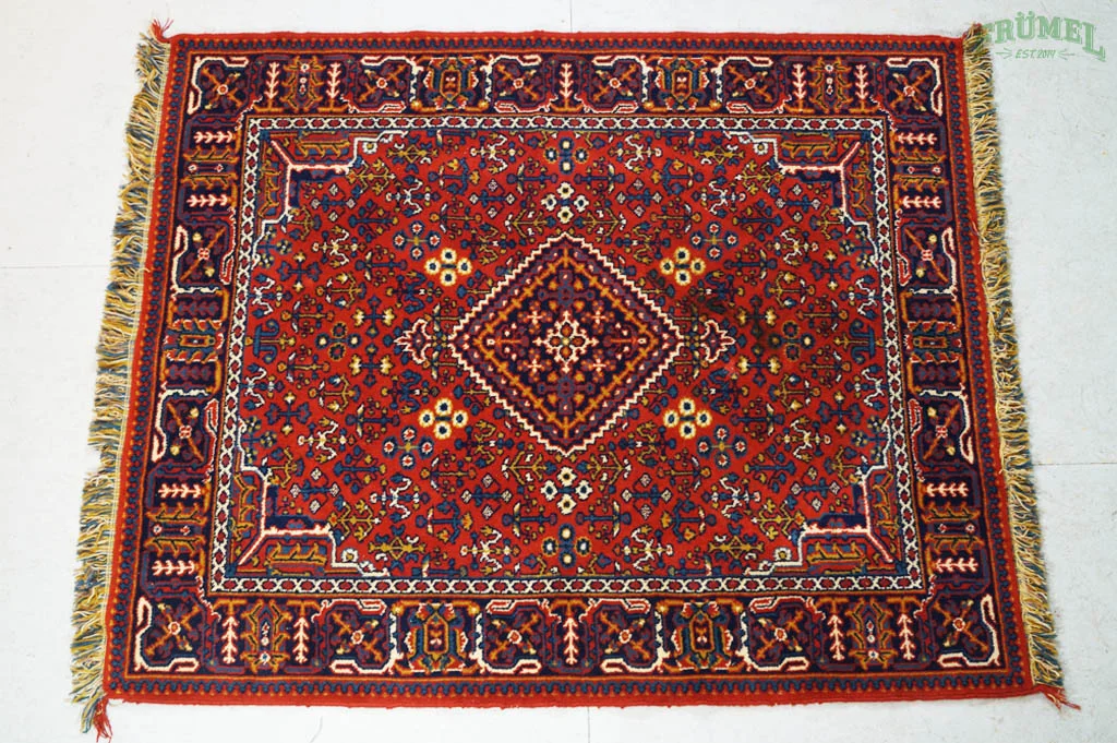 Kleurrijk traditioneel Tapijt met rood, blauw, wit en geel patroon, franjes aan de rand.