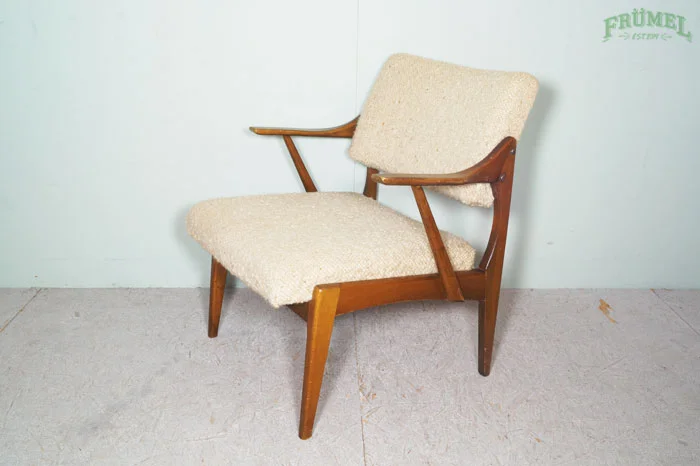 Vintage armstoel met houten frame en beige bekleding in een kamer met een lichtblauwe muur.