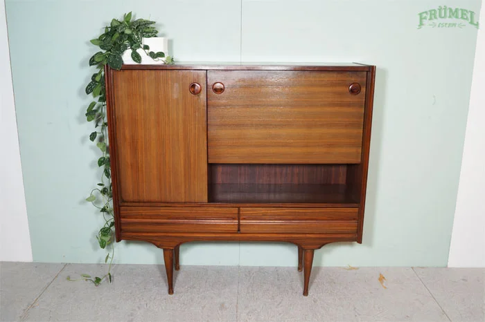 Een houten vintage dressoir met drie lades en een open vak, versierd met een groene plant op de linkerbovenhoek.