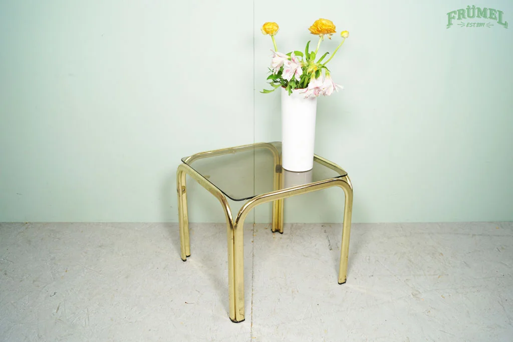 Een witte vaas met bloemen op een tafel met gouden poten