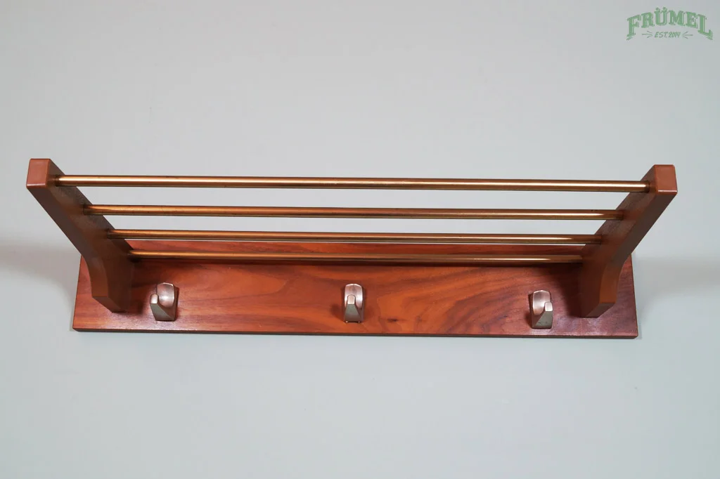 Houten en metalen kapstok met drie haken op een grijze tafel.