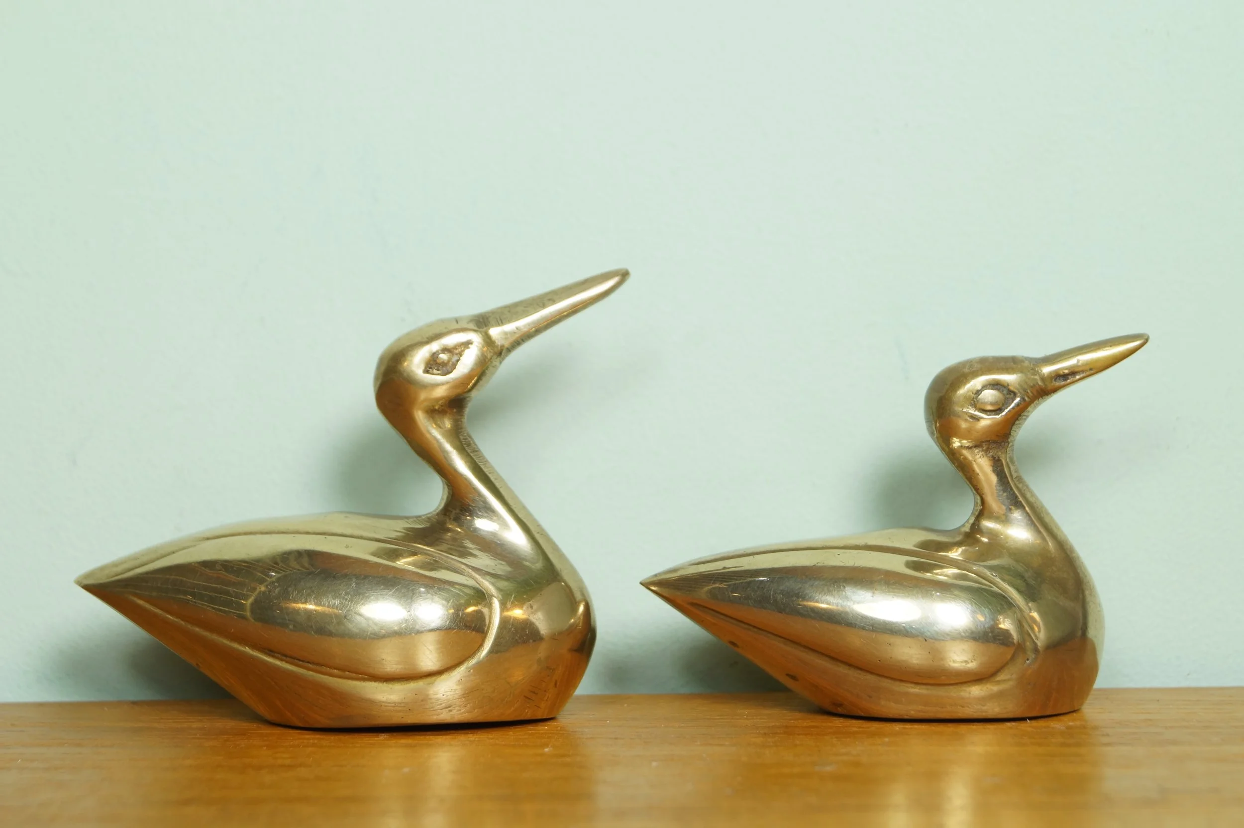 Twee gouden eendenbeeldjes op een houten oppervlak