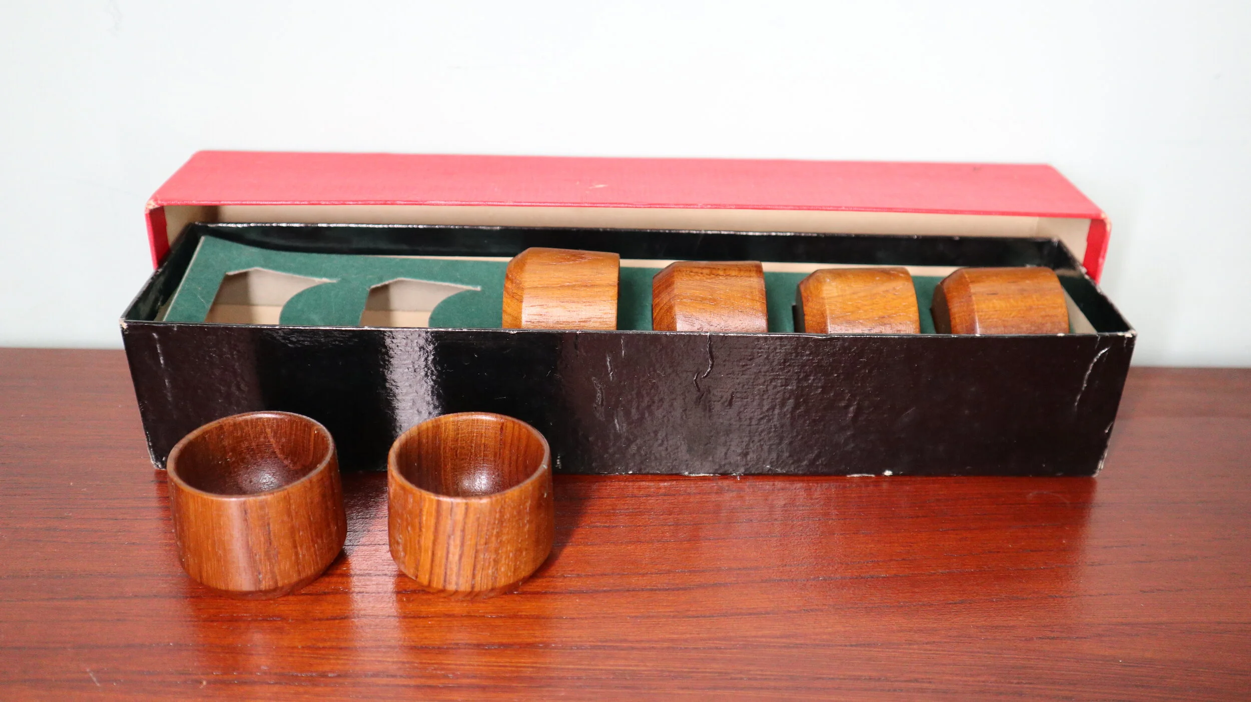Set met vier houten ronde stoppers en twee bijpassende kopjes op een houten tafel, met een doos erachter.