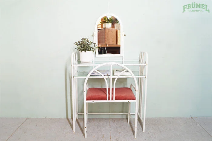 Kleedkamer met witte metalen kaptafel met spiegel, rode zitting, plantenpot en muur met logo 'FRÜMET' op lichte muur