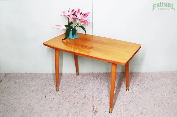 Houten salontafel met een vaas met roze en witte bloemen op een witte achtergrond.