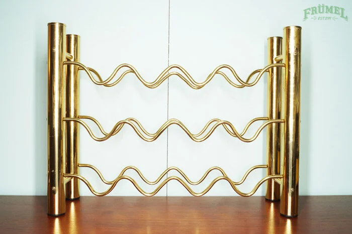Goudkleurige wijnrek met drie wijnrekken, geplaatst op een houten tafel.