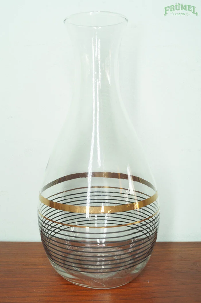 Een glazen vaas met zwart en goudkleurige cirkelpatronen, geplaatst op een houten oppervlak.