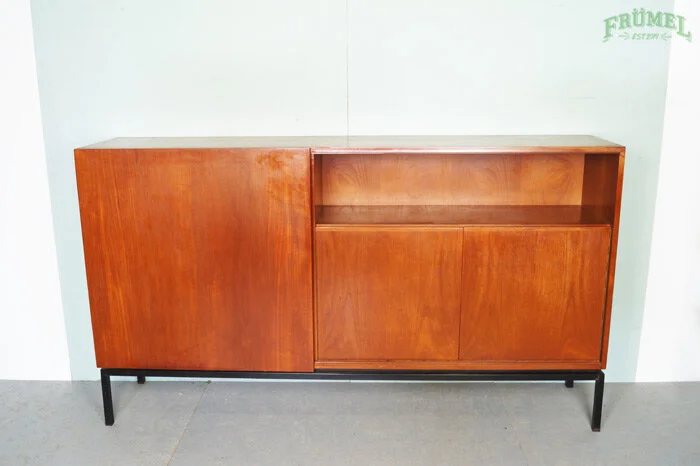 Houten kast met zwarte poten, dubbele schuifdeuren en open vak, geplaatst tegen een witte muur.
