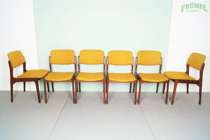 Vijf houten stoelen met gele bekleding staan in een rij tegen de muur.