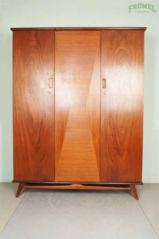 Een vintage houten kast met drie deuren en een schuine onderste rand, staande op vier poten.