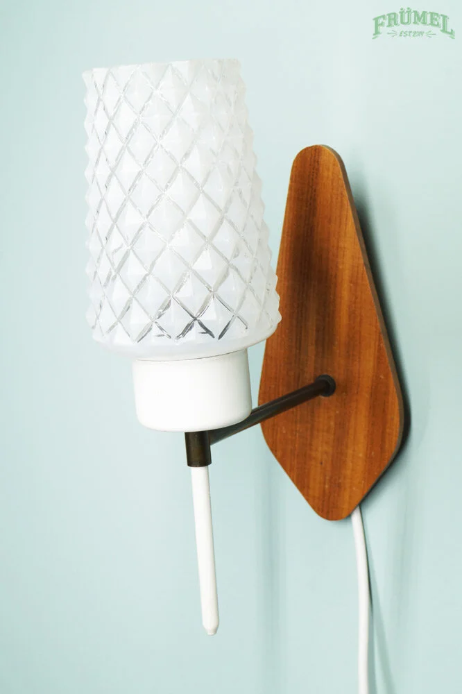 Wandlamp met witte armatuur, houten backplate, en een witte lampenkap met een diamantpatroon, bevestigd aan een lichtblauwe muur, met het logo 'FRÜMEL' in de hoek.