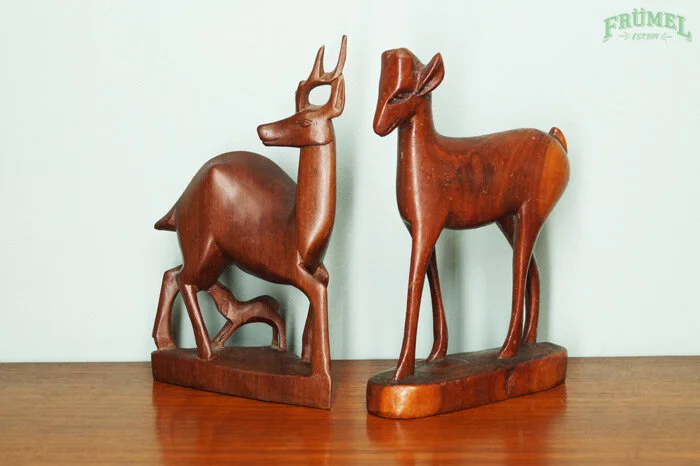 Houten beeldjes van een hert en een hert met geweien, geplaatst op een houten oppervlak.