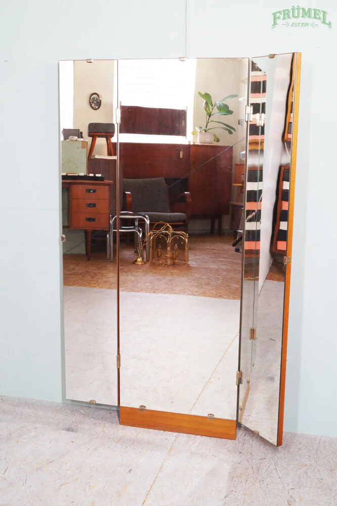 Een gedeeltelijk open houten en spiegelende kamerscherm met een glas in lood raam en meubels die in de reflectie zichtbaar zijn, waaronder een plant en een stoel.