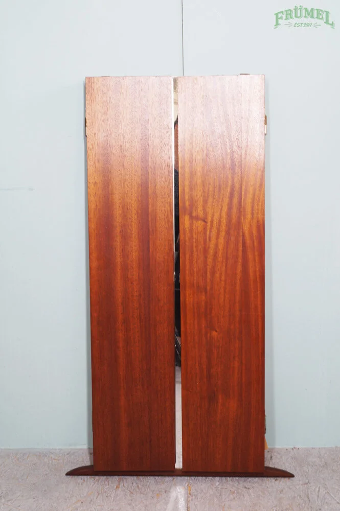 Een houten kast met dubbele deuren, erachter lijken decoratieve objecten of meubels te zitten.