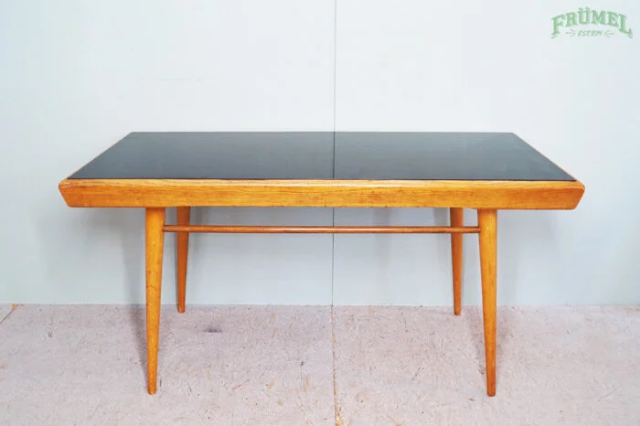 Een houten tafel met een zwart oppervlak tegen een witte muur.