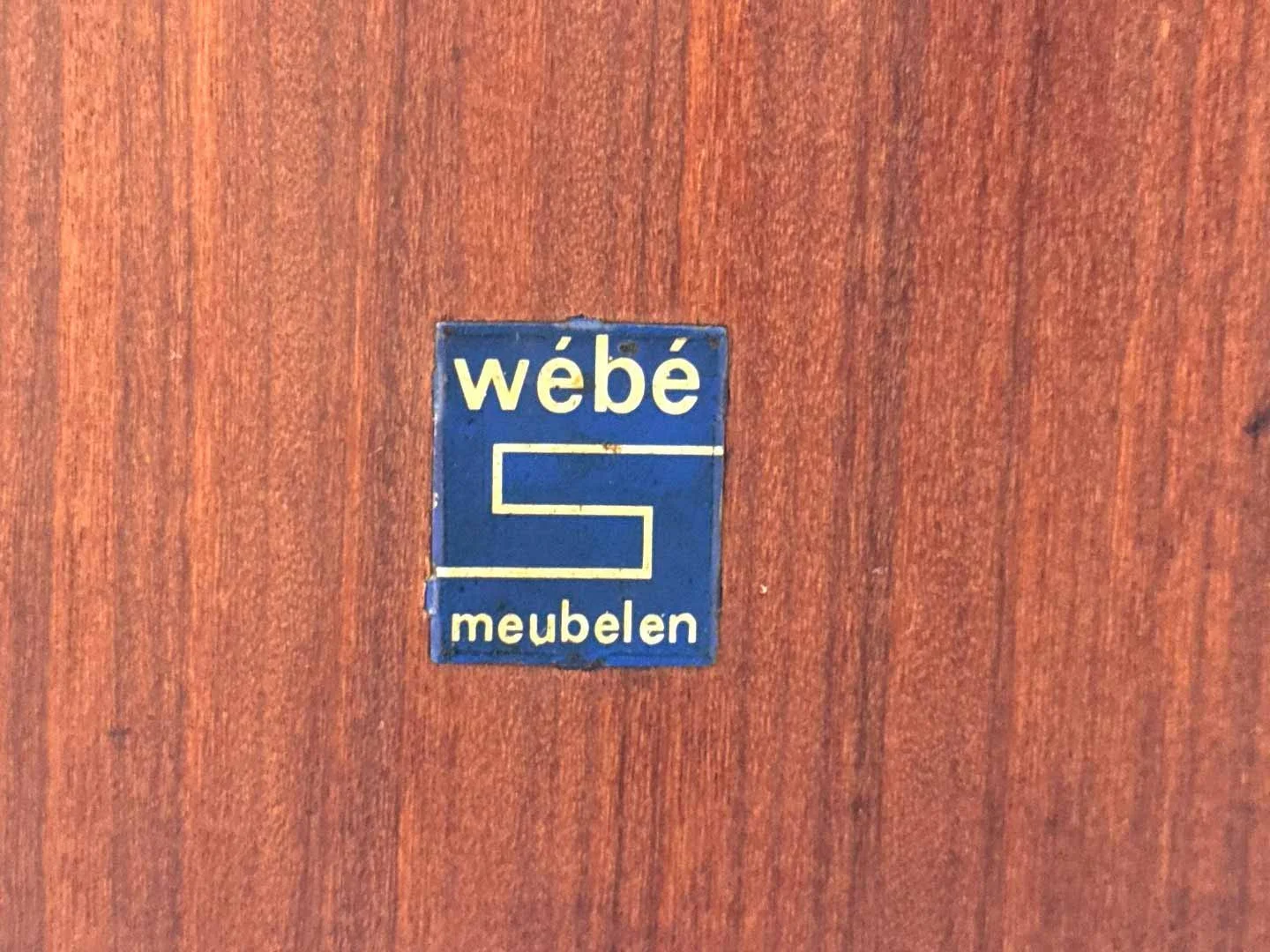 Wébé merksticker op Louis van Teeffelen meubel, authentiek Dutch design label jaren 60.