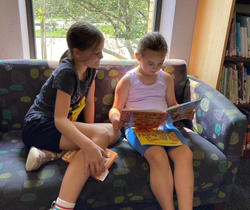 Alexandra Bradshaw, 8, and Taylor Wood, 7, enjoy some quiet time with their books in the Children's Room