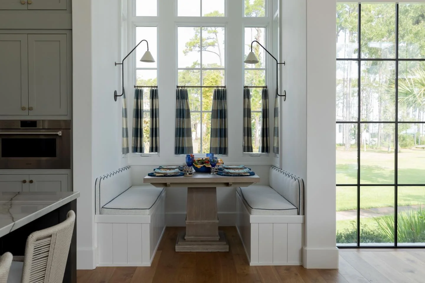 I adore this cozy nook with banquette seating! The large blue window checks and scalloped backs on the custom cushions make it truly special. 😍