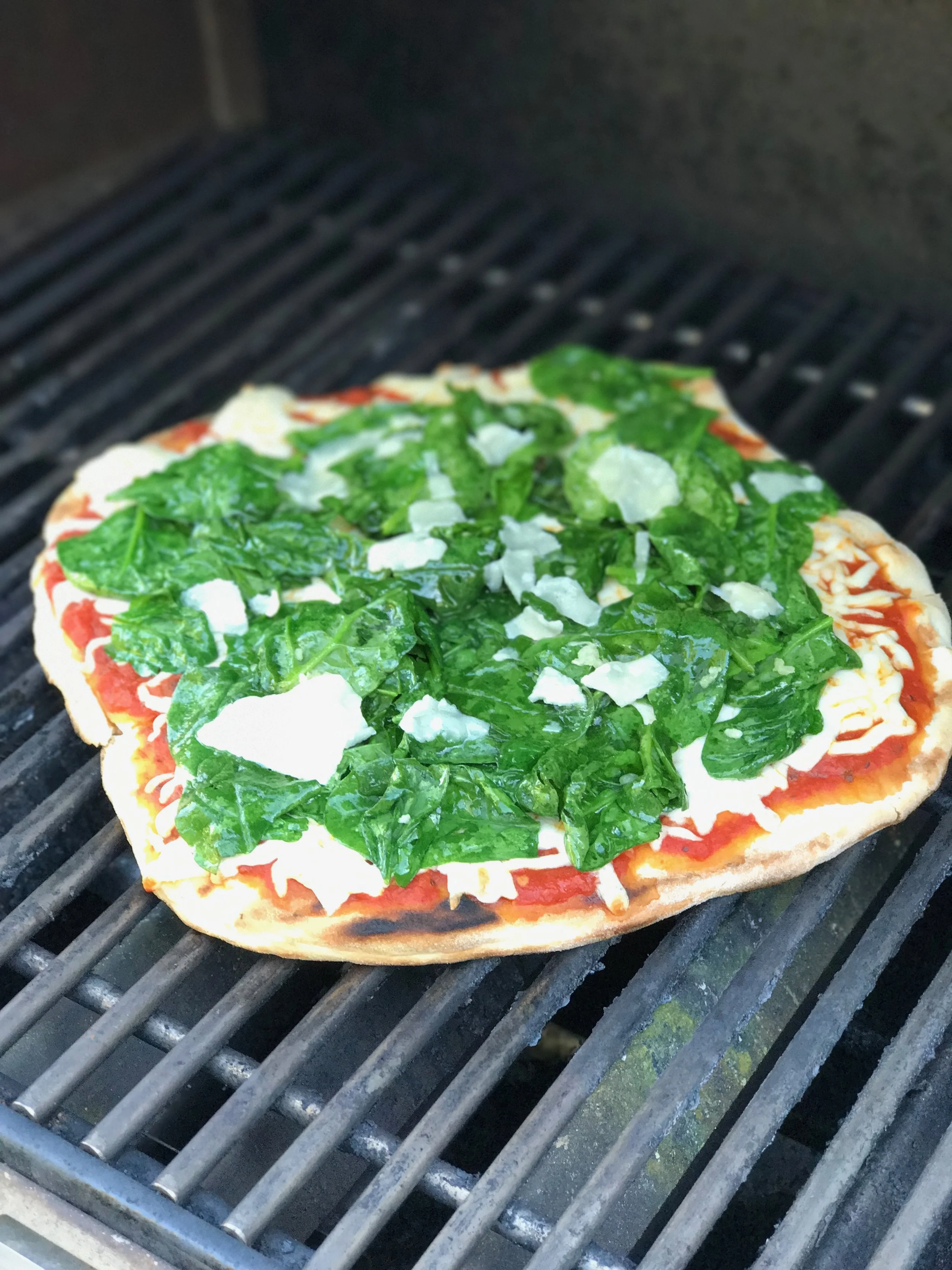 The second pizza was topped with regular pizza sauce and mozzarella before closing the lid to melt the cheese. In the meantime I sautéed spinach with olive oil and two cloves of minced garlic until it just began to wilt. Then I tossed it on top of the pizza with some shaved parmesan and let it cook another minute more.