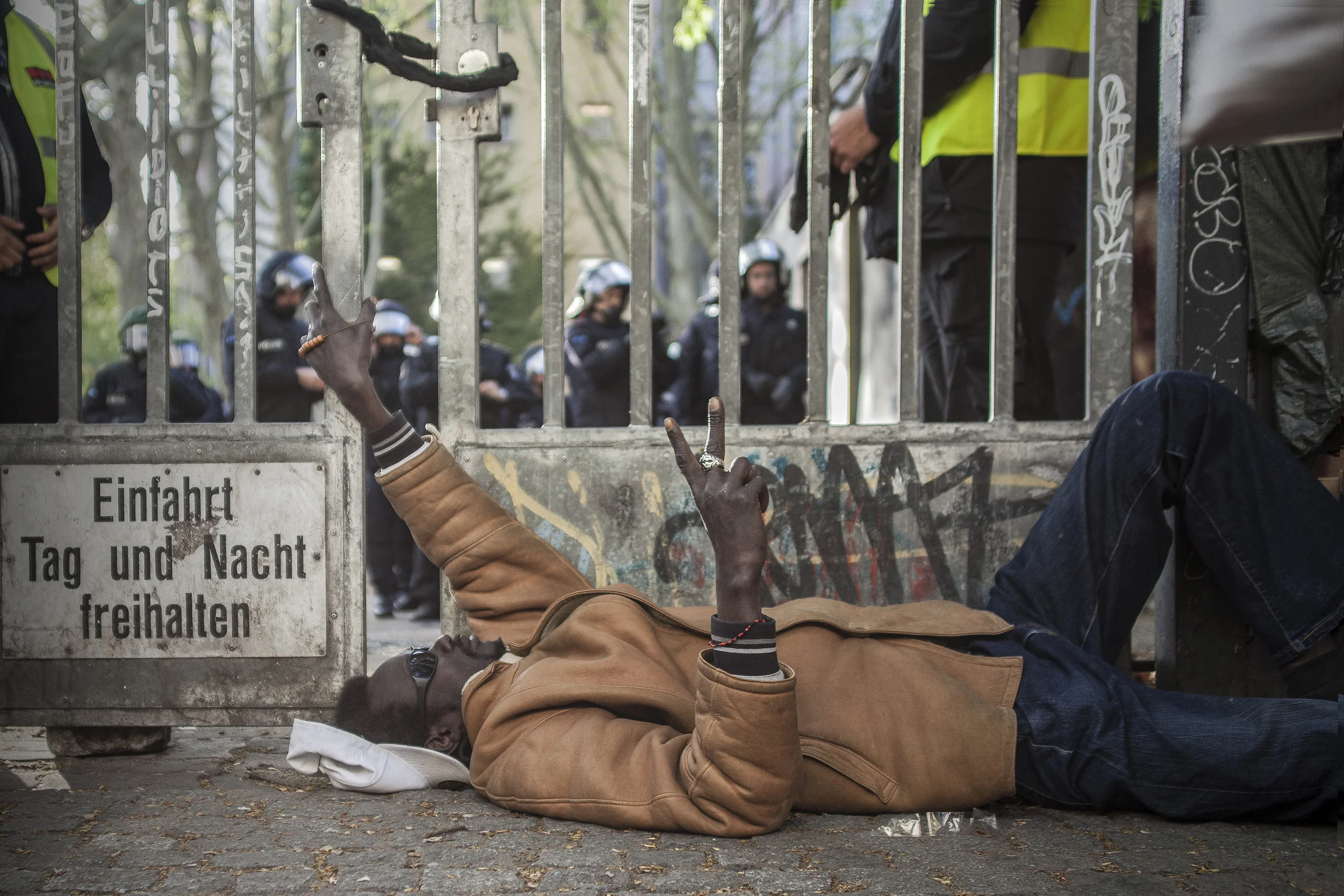 1 May, 2015 - Berlin, Germany Protester by the gates of the Gerhart-Hauptmann Schule. The abandoned building was formerly occupied by African asylum seekers until they were forcibly removed one month prior. In anticipation of the annual massive May 1st demonstrations in Berlin police accompanied by service dogs fortified the complex's entrance.