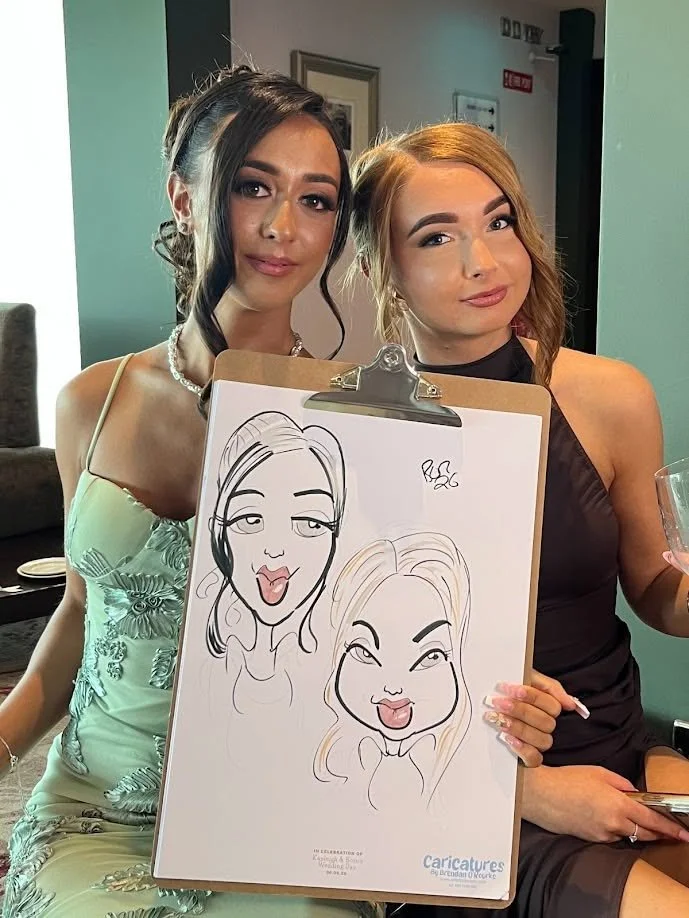 Two young wedding guests holding their finished live caricature.