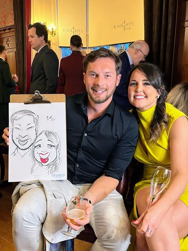 Guests holding their live caricature drawing during a wedding drinks reception at Clontarf Castle in Dublin.