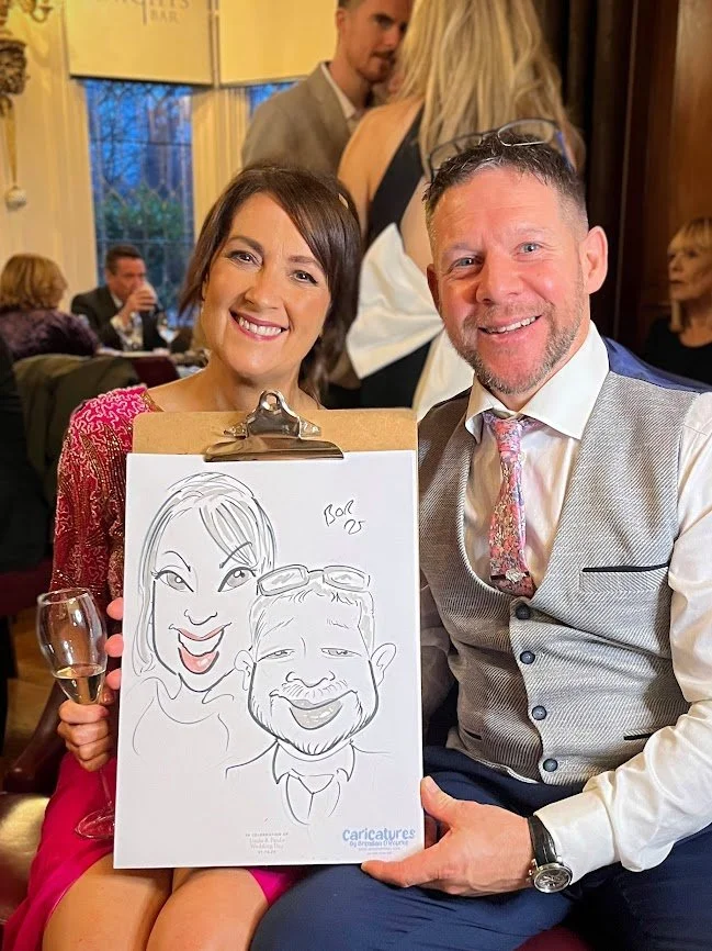 Wedding guests smiling while holding their caricature drawing created during a drinks reception at Clontarf Castle, Dublin.