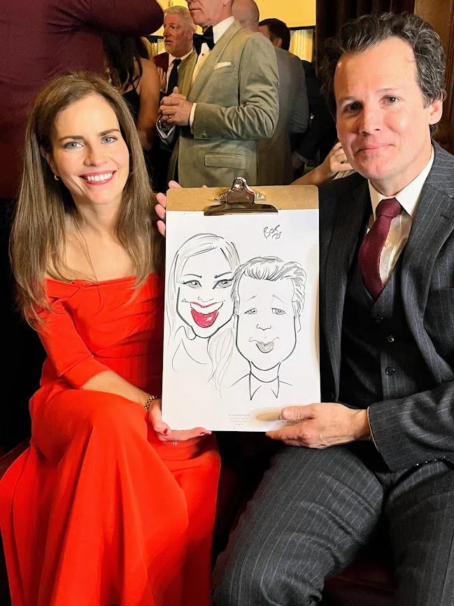 Couple posing with their live caricature portrait at a wedding drinks reception in Clontarf Castle, Dublin.