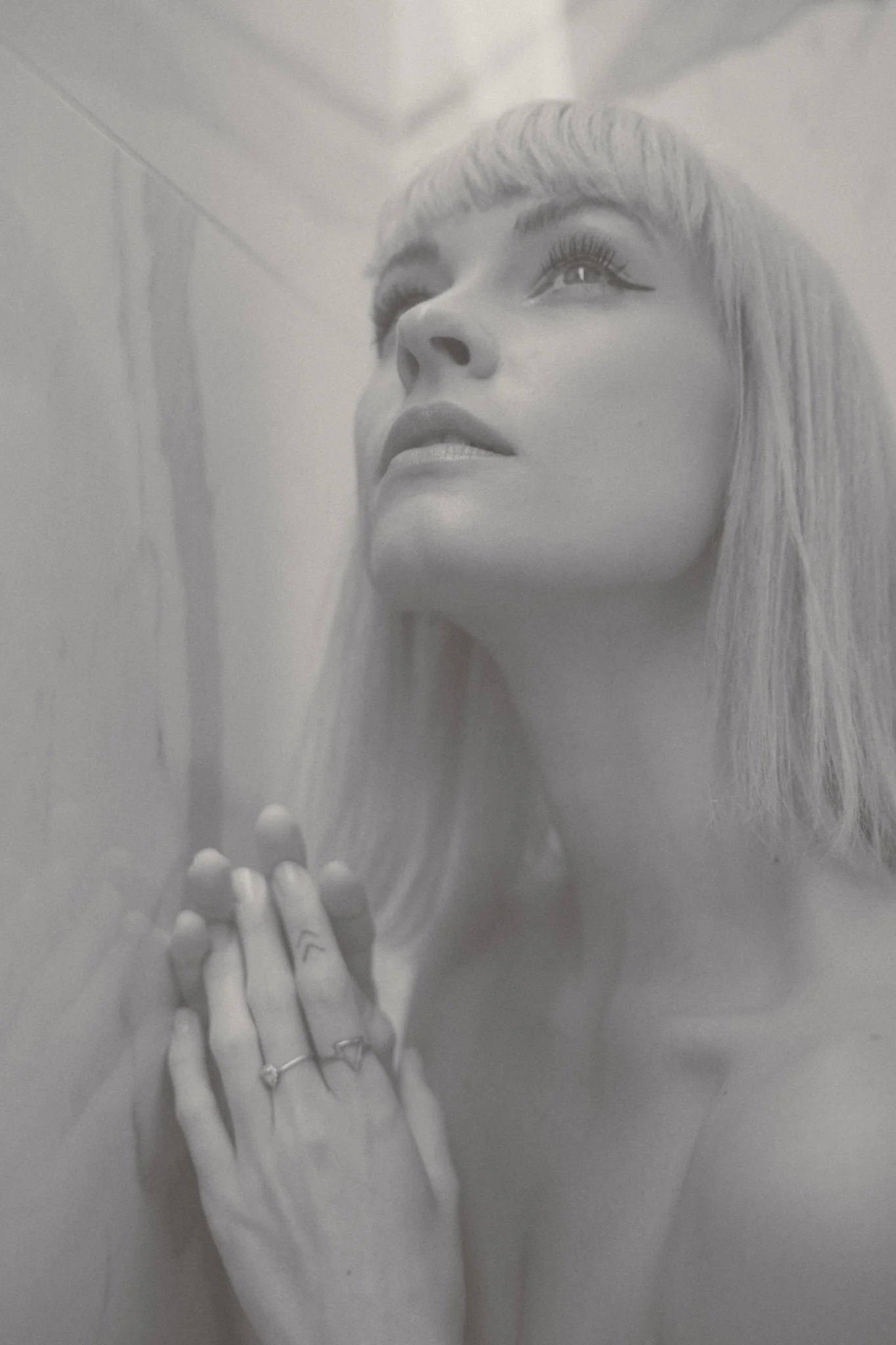 Black and white photo of a woman with long hair, closed eyes, and hands in prayer or meditative pose, with a calm expression.