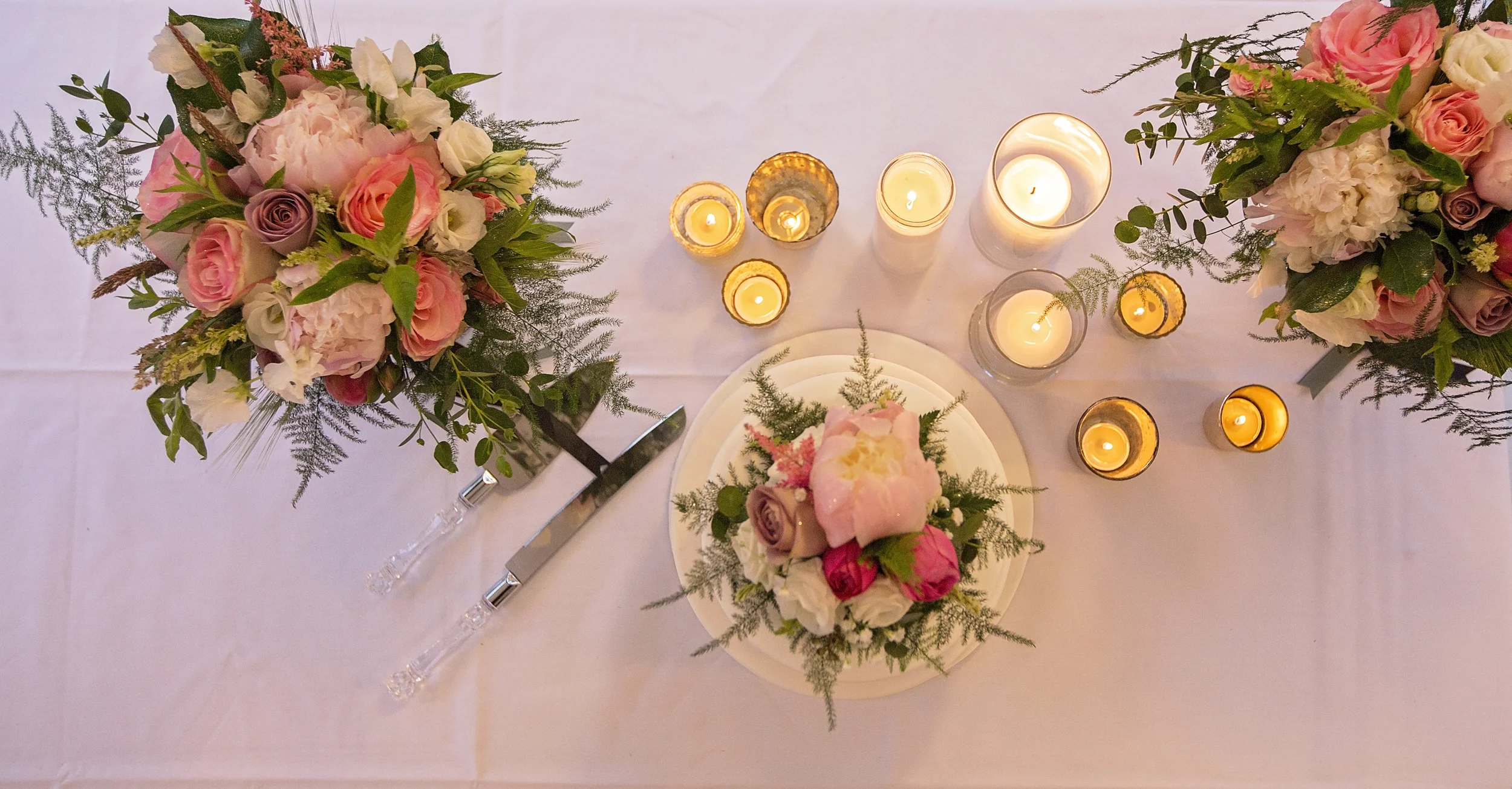 Beautiful shot of the cake table decorated with bridal bouquets.