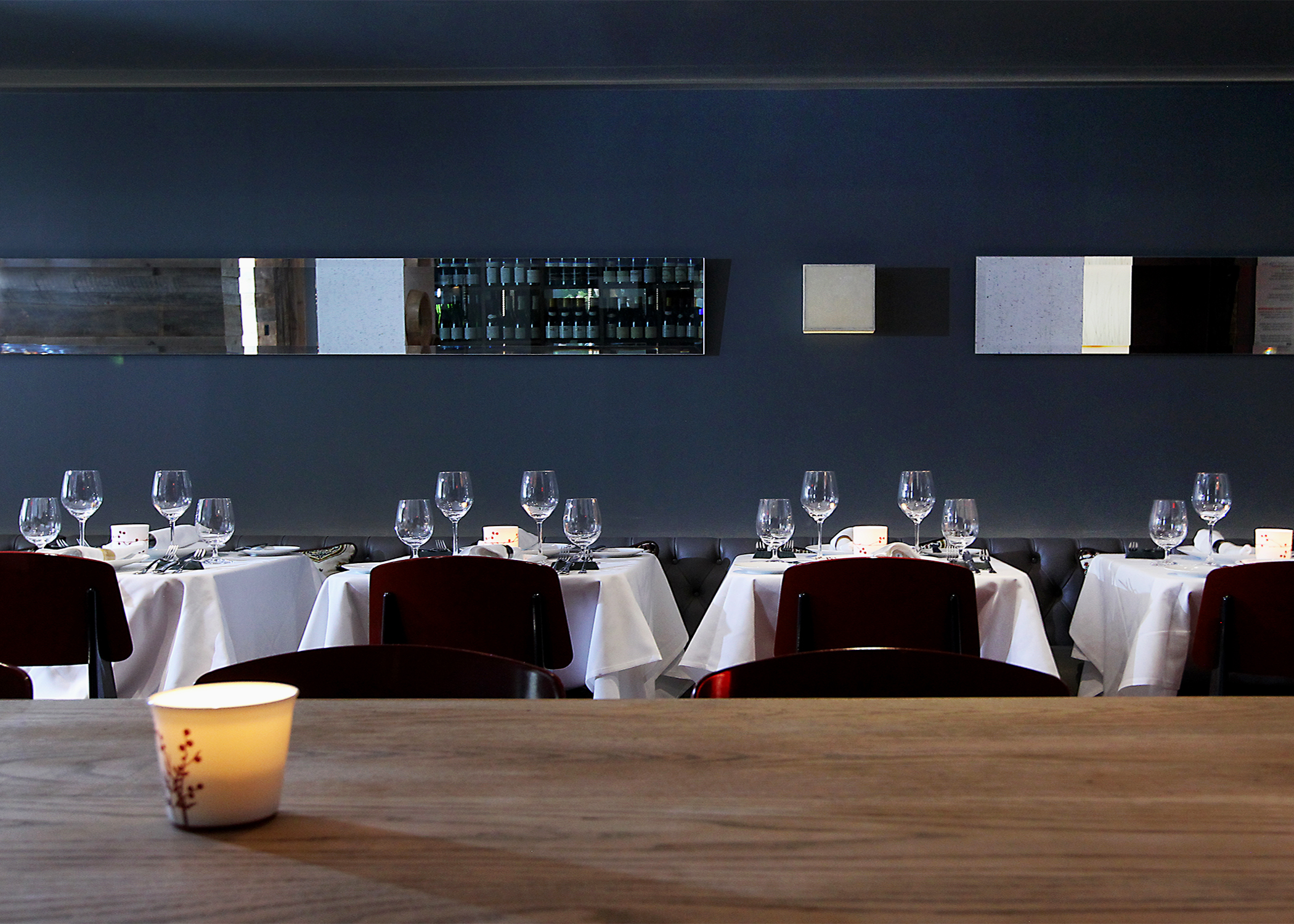 The main dining space was refreshed with a central floating oak farm table, cork wall/ceiling linings and carefully located lighting, mirrors and artwork for an elevated fine dining experience.