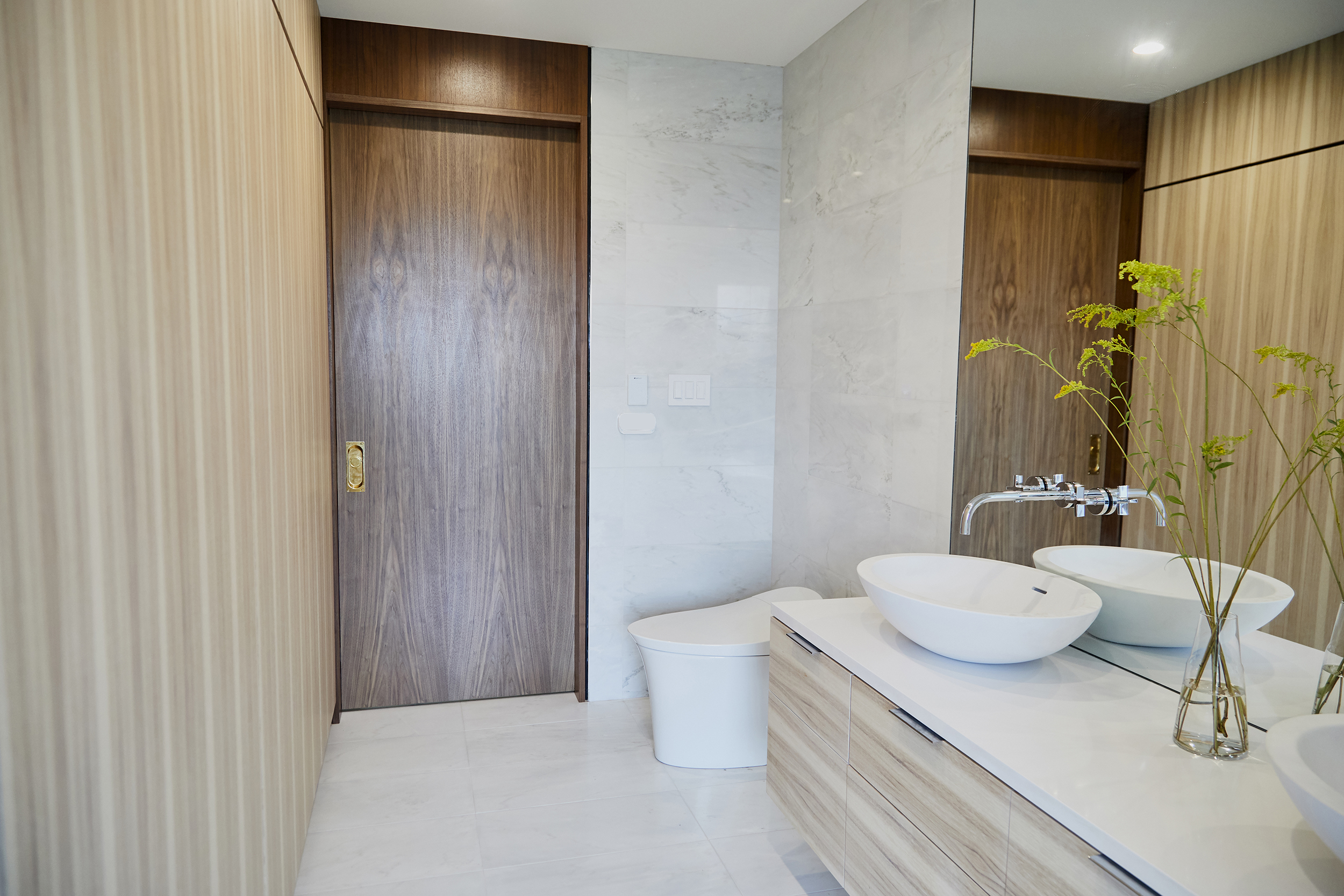 Local materials were selected throughout the house interior, here in the master ensuite pecan/hickory was chosen for the vanity and domestically quarried white marble for floors and walls