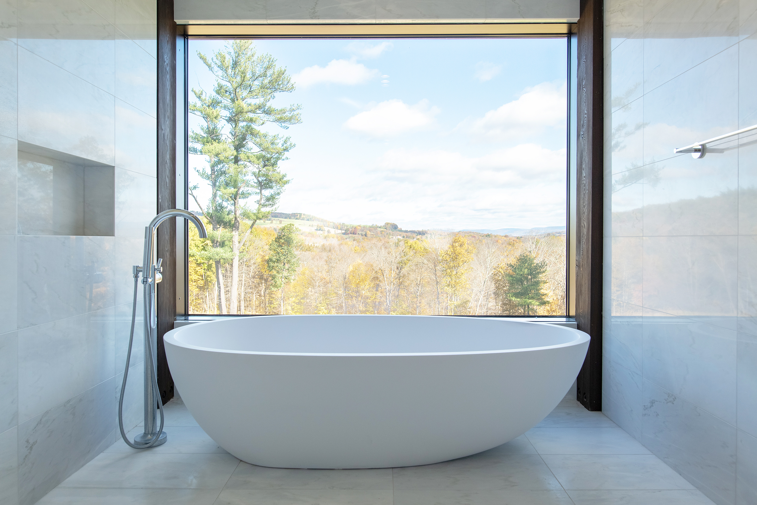 The soaking tub of the master ensuite is framed by a picture window looking out of the rural landscape towards distant mountains