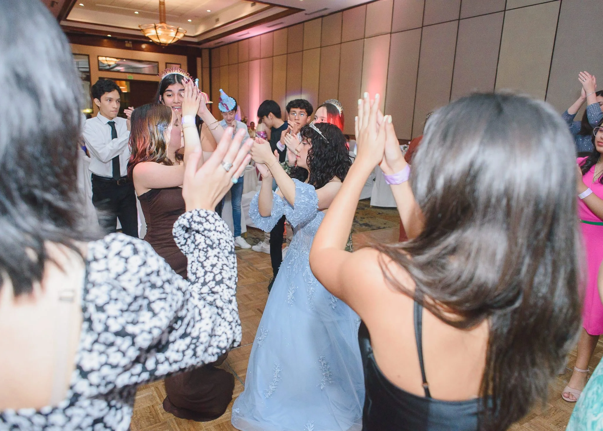 Quinceañera en Guatemala bailando en el centro de la pista junto a sus amigas e invitados en un ambiente festivo.