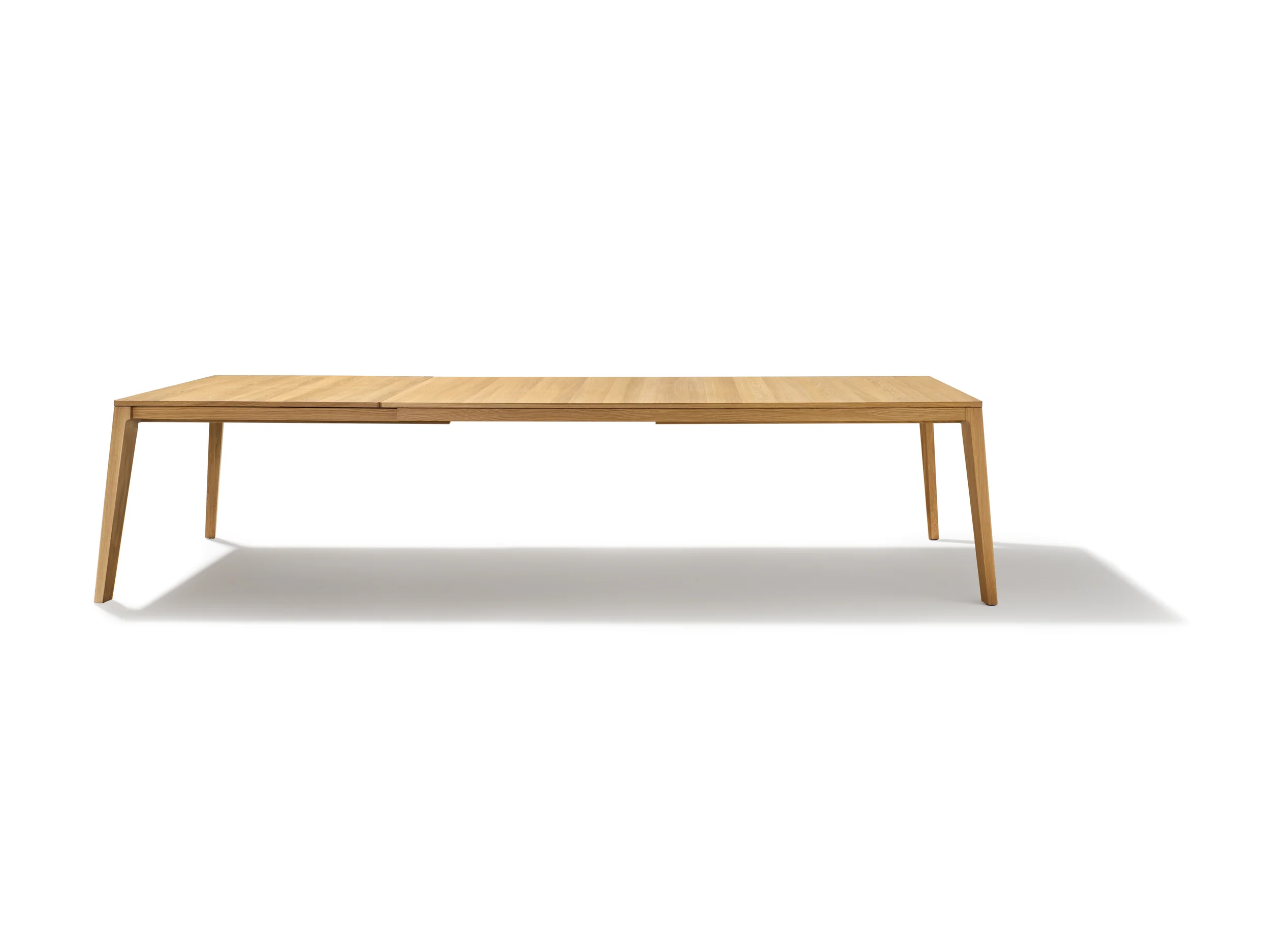 MYLON table The mylon table is an impressively organic, contemporary design. Angled, tapered table legs with rounded edges merge fluidly into the frame and lend the table a certain stability. Thanks to its finely crafted joint, the elegant table top with its eye-catching lateral wood grain seems to float above the externally flush lower part. The integrated insert panels allow you to extend the table by up to 100 cm. In other words, it can be converted from a homely table for the family into a grand centrepiece for guests. The small-format mylon table impresses thanks to its well-proportioned compactness, while in larger designs the flared legs emphasise the impressive span of the piece. Text/Photos/Producer: TEAM 7 Design: Jacob Strobel 2014
