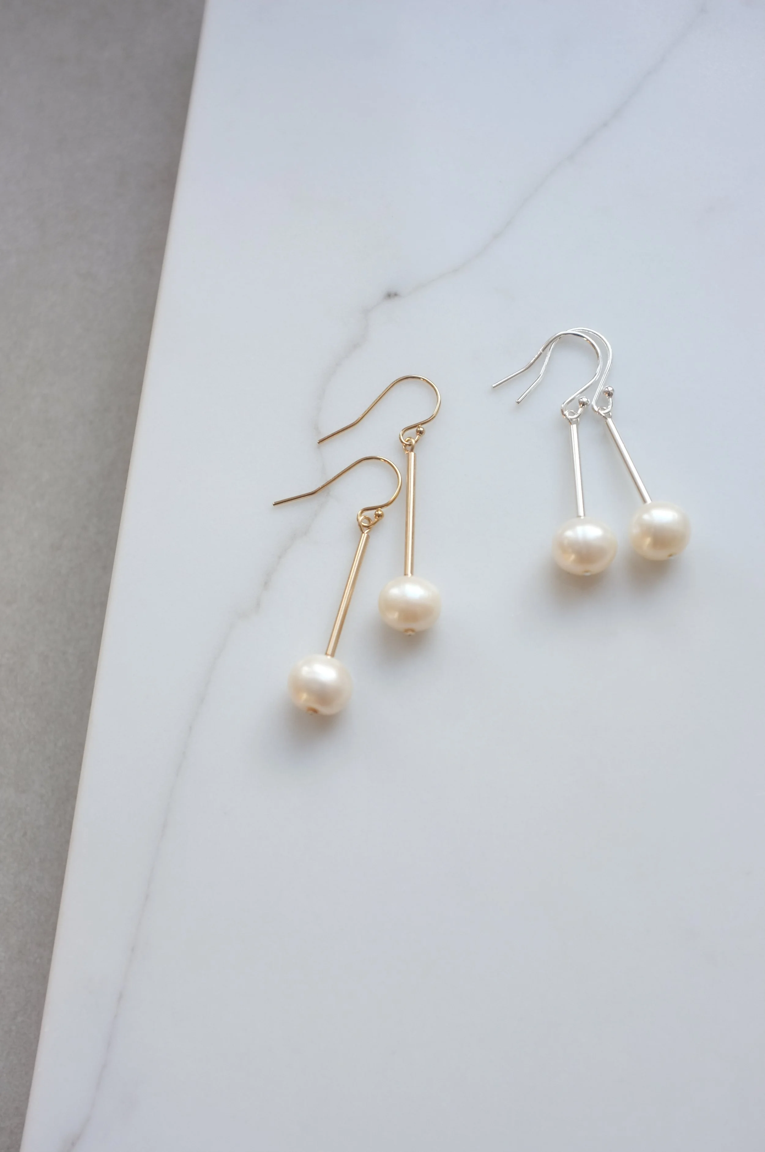 two pairs of Promise bridal earrings lay side by side, illustrating the silver or gold options.