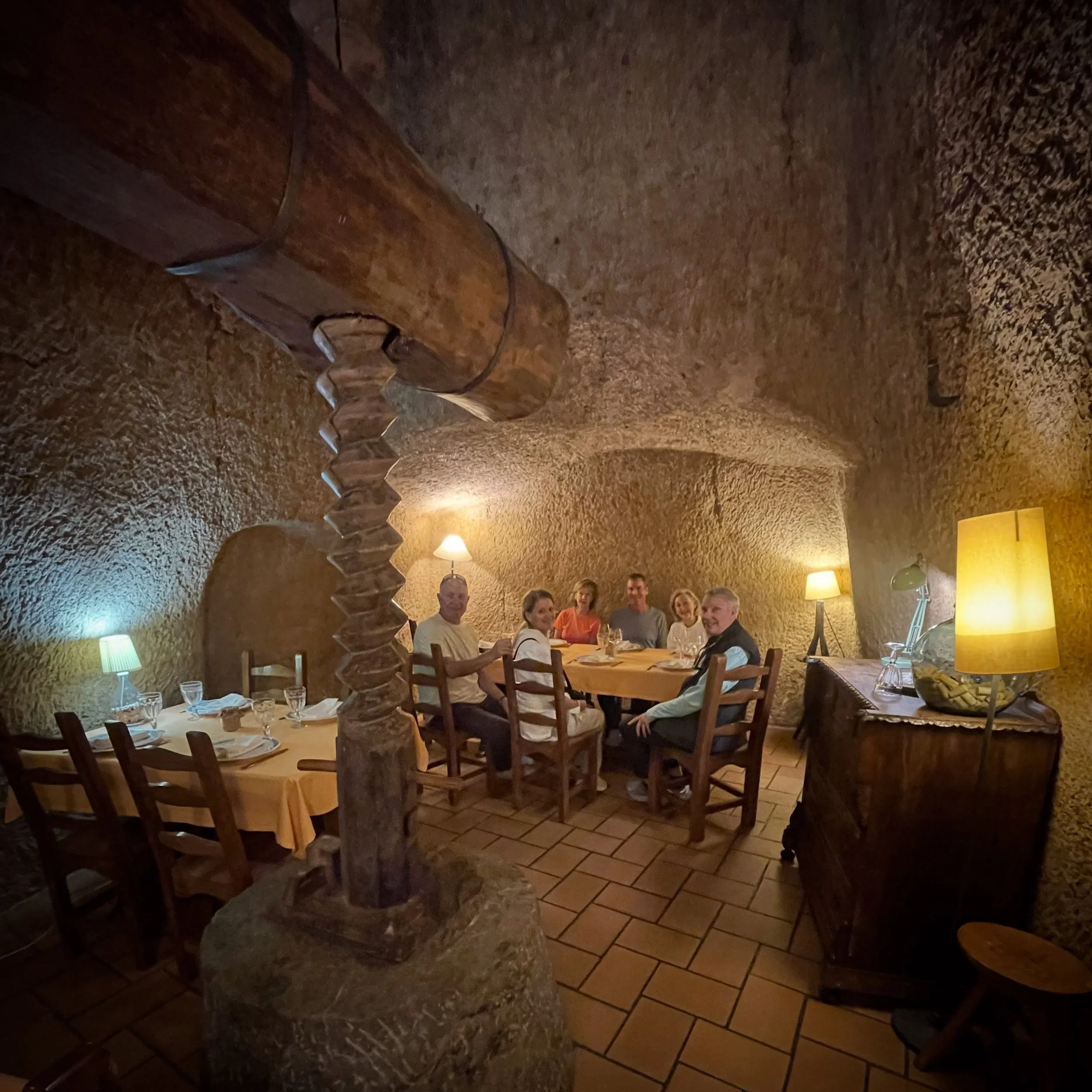 Historic Cave Dining. 10 meters underground in a historic wine cave, where grapes were brought from harvest, to be pressed into must (press arm, screw and weight in foreground), to fill casks for fermentation into wine and then storage for sale, befo