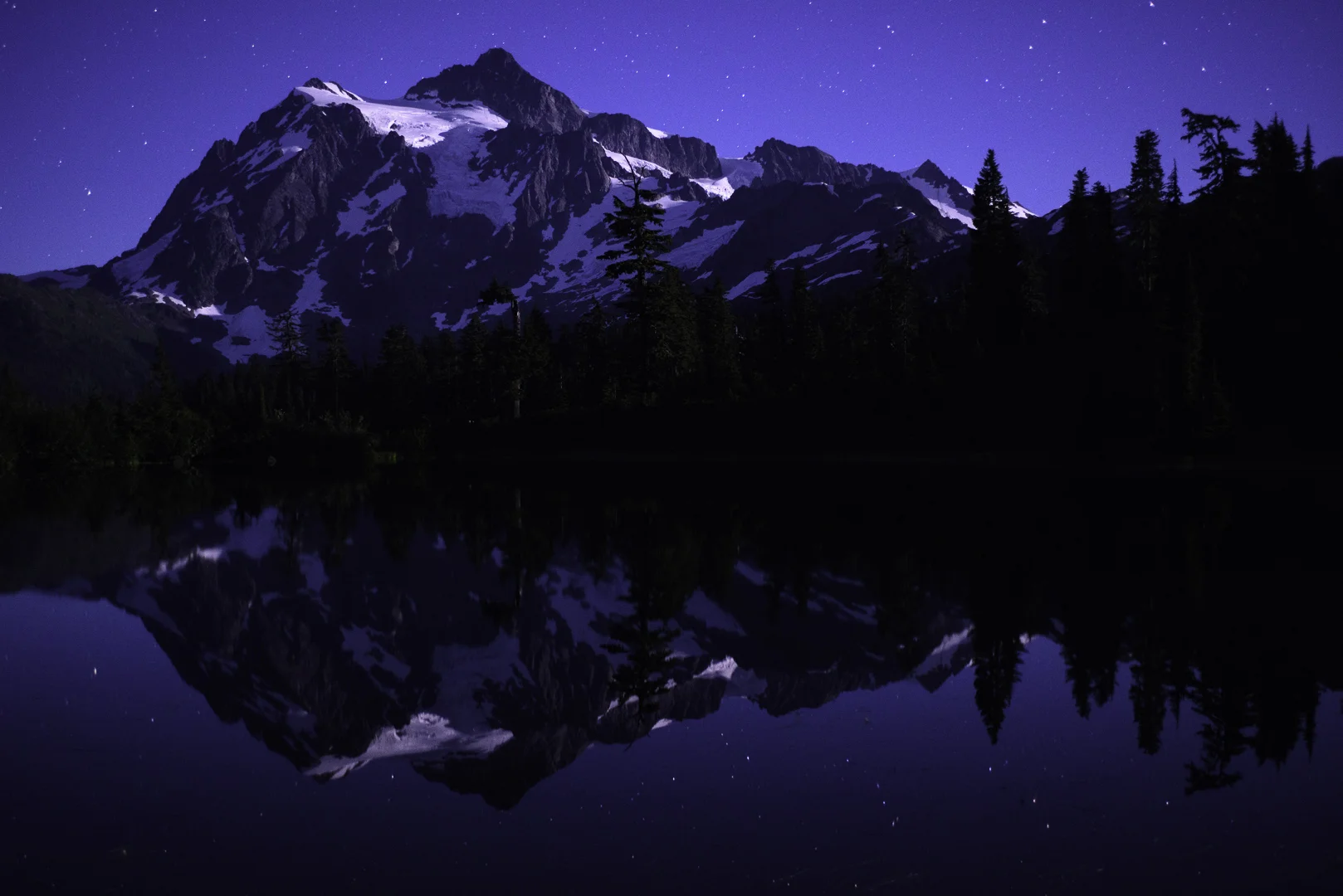 Mount Shuksan in North Cascades National Park sits reflected under a starry summer sky. © 2016 Chris Nicholson.